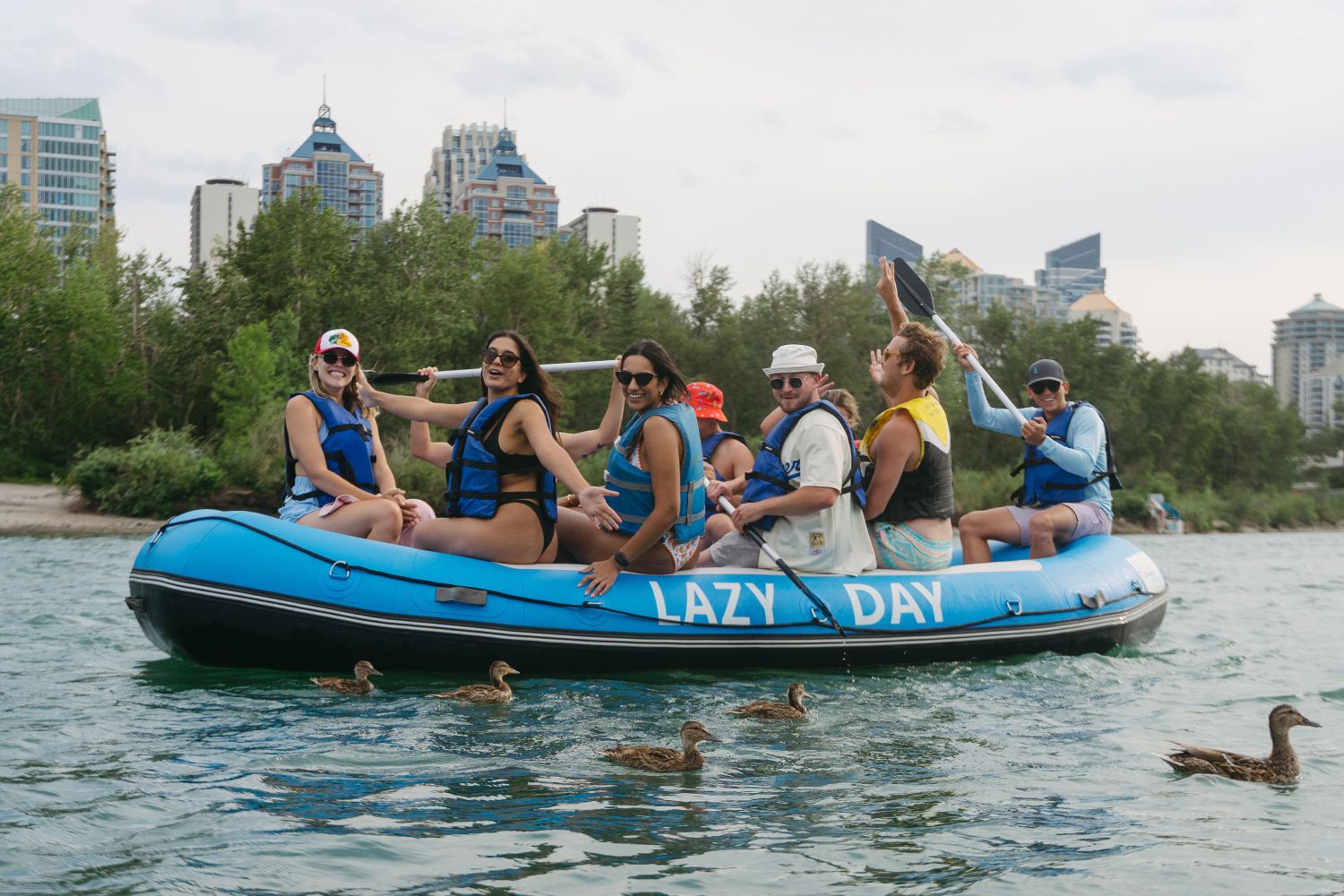 a group of people riding on the back of a boat in the water watching the ducklings float by